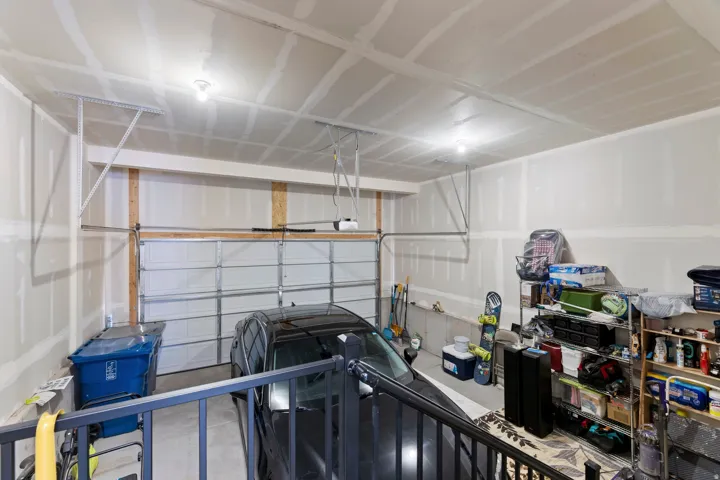 Attached garage with concrete flooring, drywall walls, and overhead lighting
