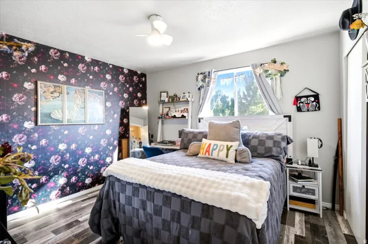 LVP flooring, ceiling fan, window with exterior scenery, floral accent wall