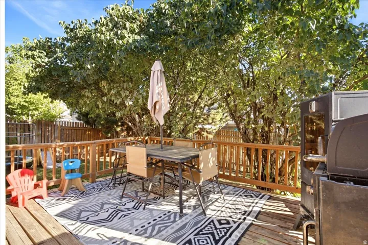 Wood deck with a natural wood railing, surrounded by mature trees, and a wood fence