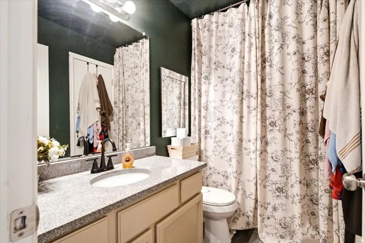 Vanity with a granite-style countertop, undermount sink, and dark-finish faucet