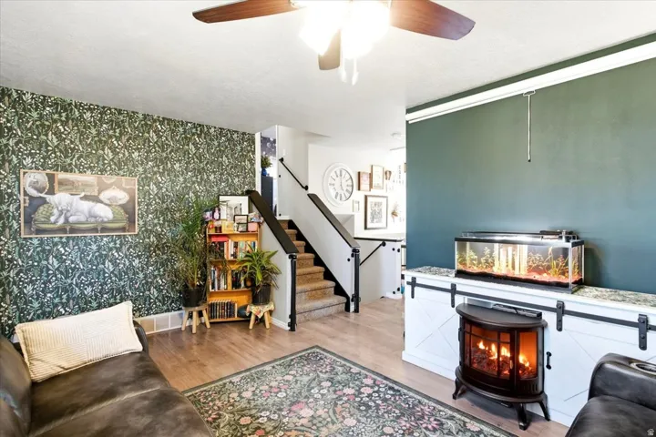 LVP flooring, accent wall with patterned wallpaper, built-in storage cabinet with barn door hardware, and staircase with dark balusters