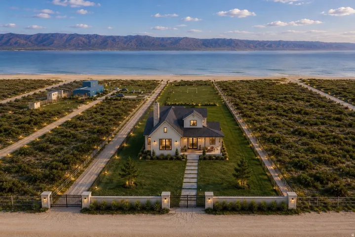 Gated entry with stone pillars, gravel driveway, and manicured lawn