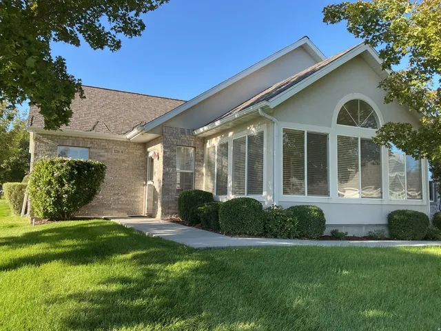 Brick and stucco exterior with a prominent sunroom featuring large windows and an arched transom