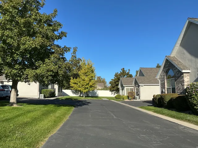 Paved driveway with surrounding mature trees and manicured lawns