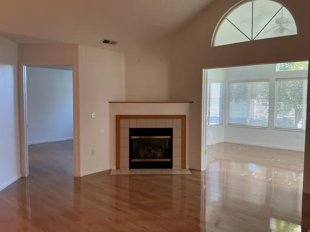 Wood-finish flooring throughout, vaulted ceiling, and a fireplace with a tiled surround