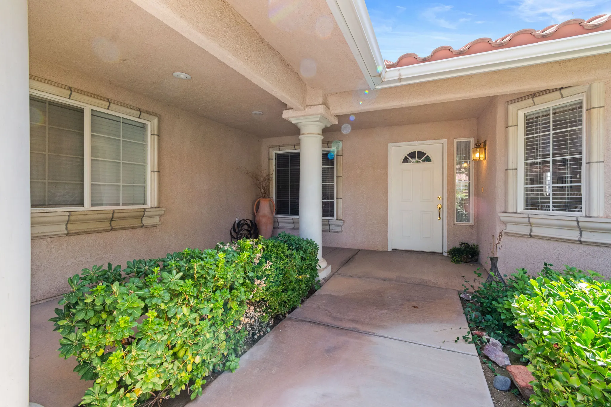 Covered entry with support columns, stucco exterior, and red tile roof