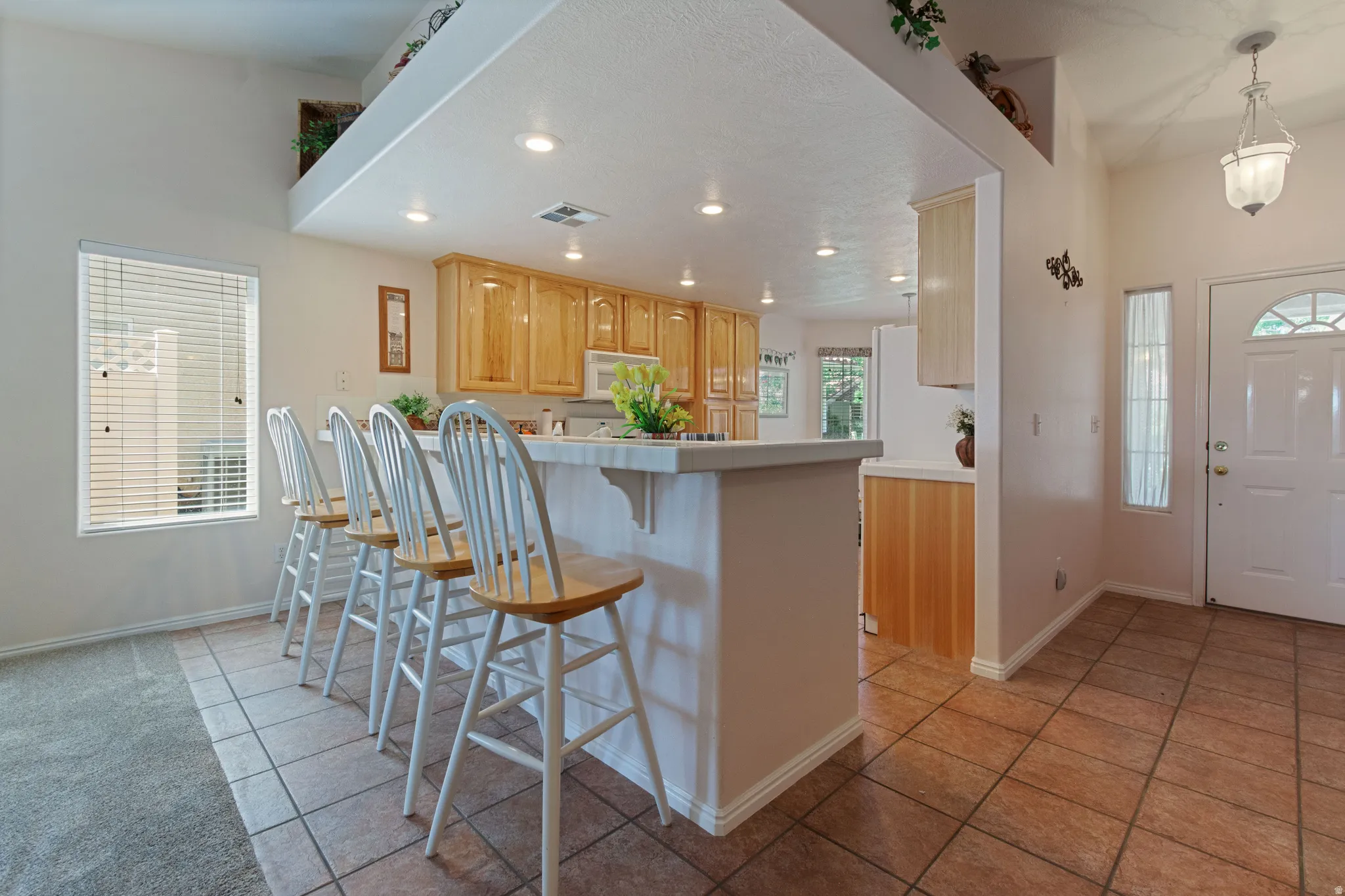 Kitchen with wood-finish cabinetry, recessed lighting, a breakfast bar, and tile flooring