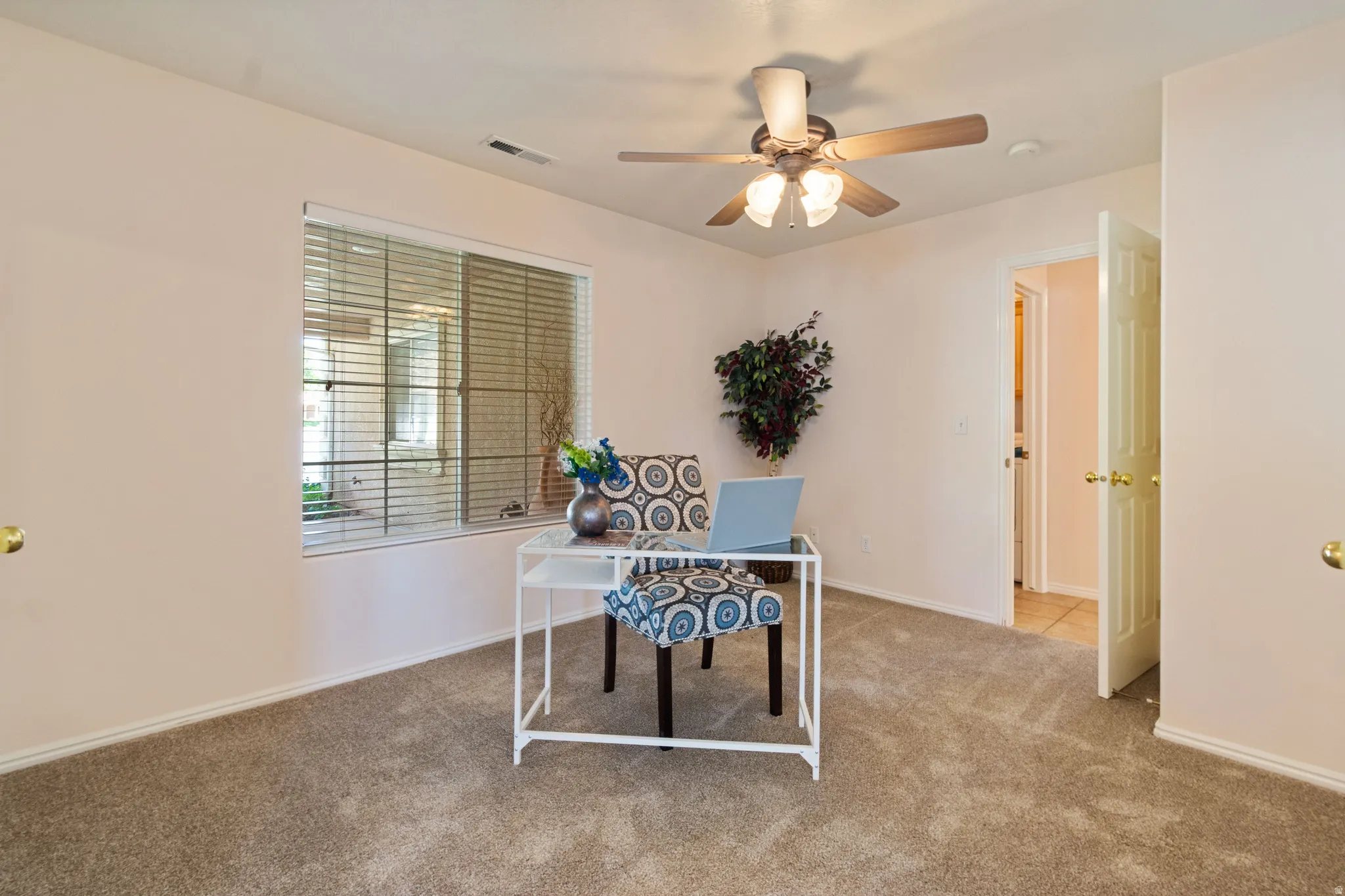 Light-toned wall paint, neutral carpet flooring, and a ceiling fan with integrated lighting