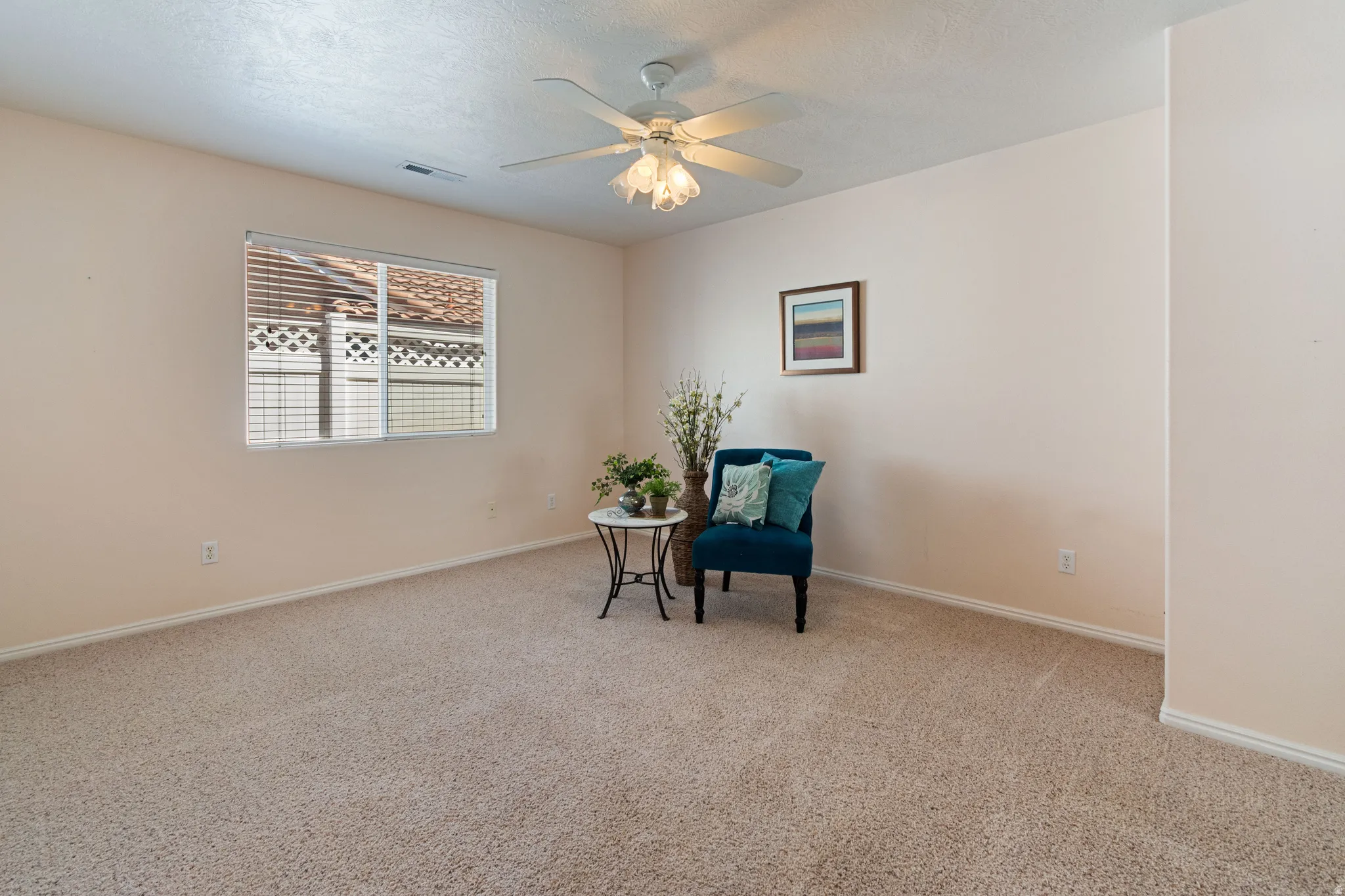 Generous room with neutral-toned carpeting, a single window with blinds, and a ceiling fan with integrated lighting