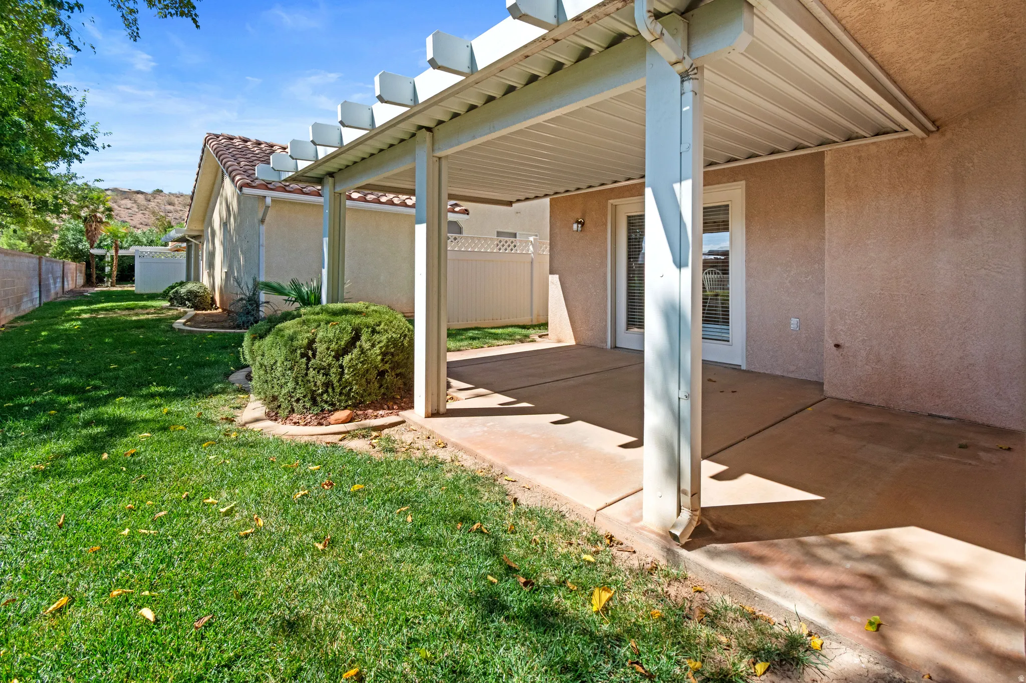 Covered patio with an attached pergola, stucco exterior, tile roofing, and a manicured lawn