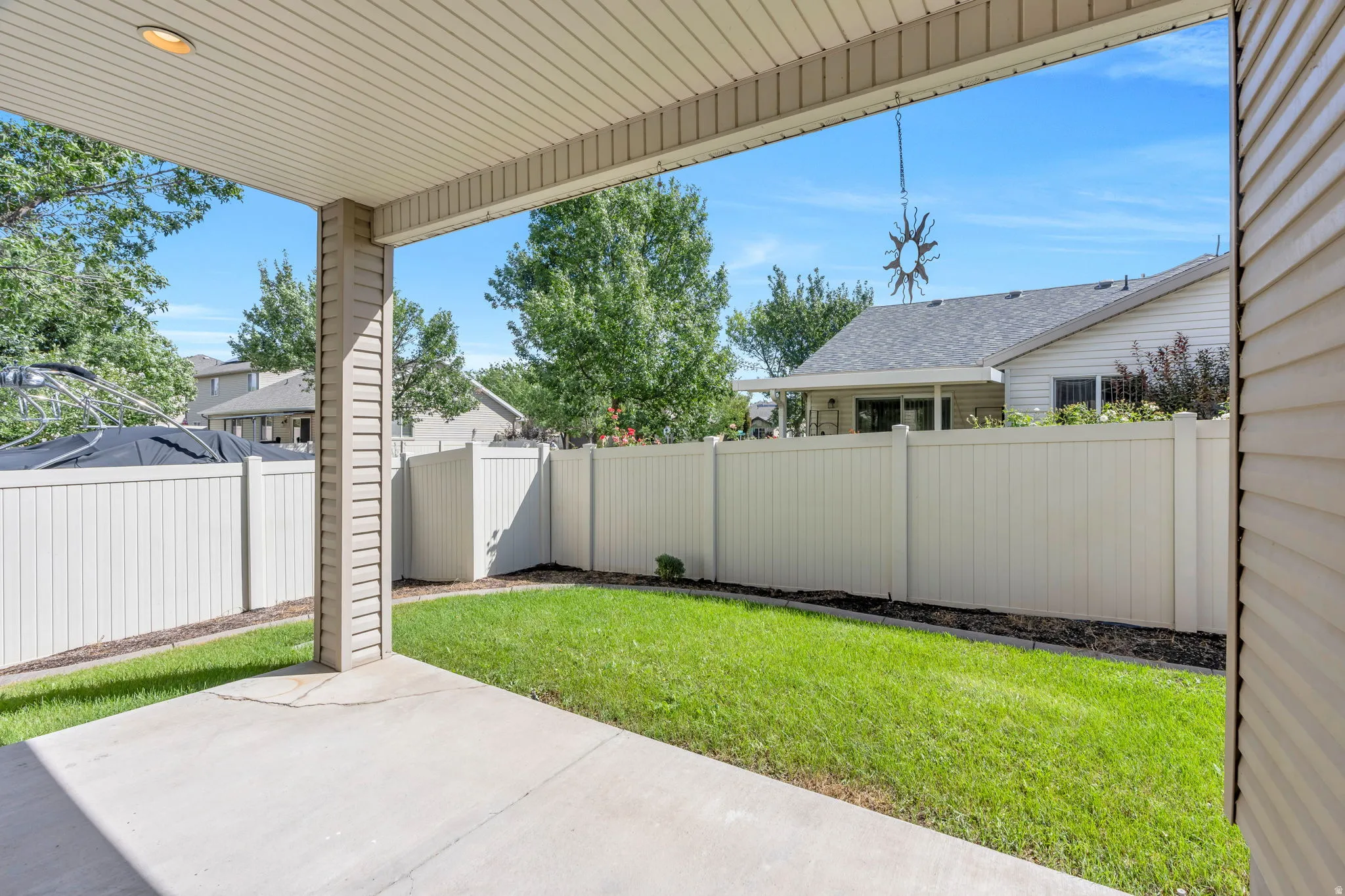 Covered patio featuring a concrete slab and a fenced backyard with a grass lawn