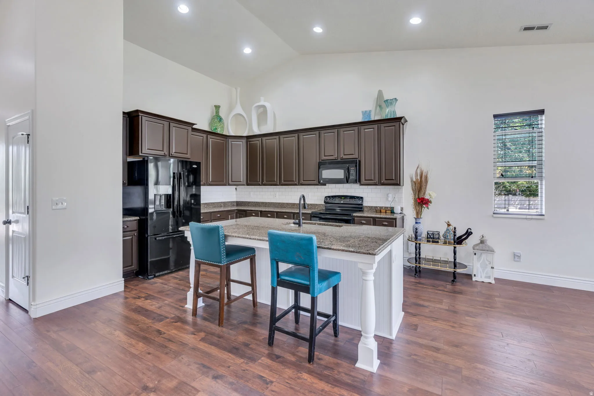Kitchen featuring dark wood-finish cabinetry, granite countertops, and a white subway tile backsplash