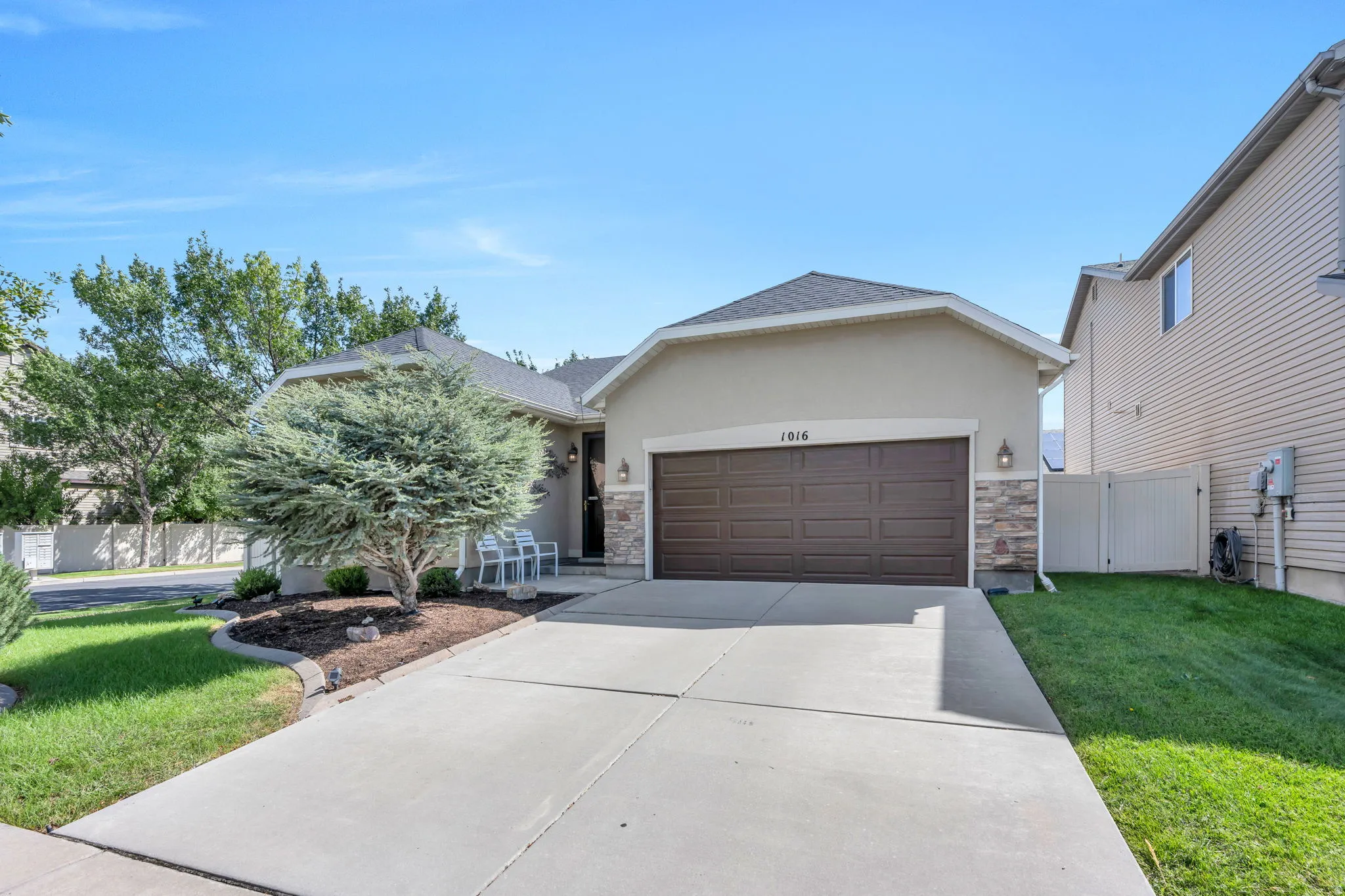 Stucco exterior with stone accents, concrete driveway, attached two-car garage, and a covered entryway