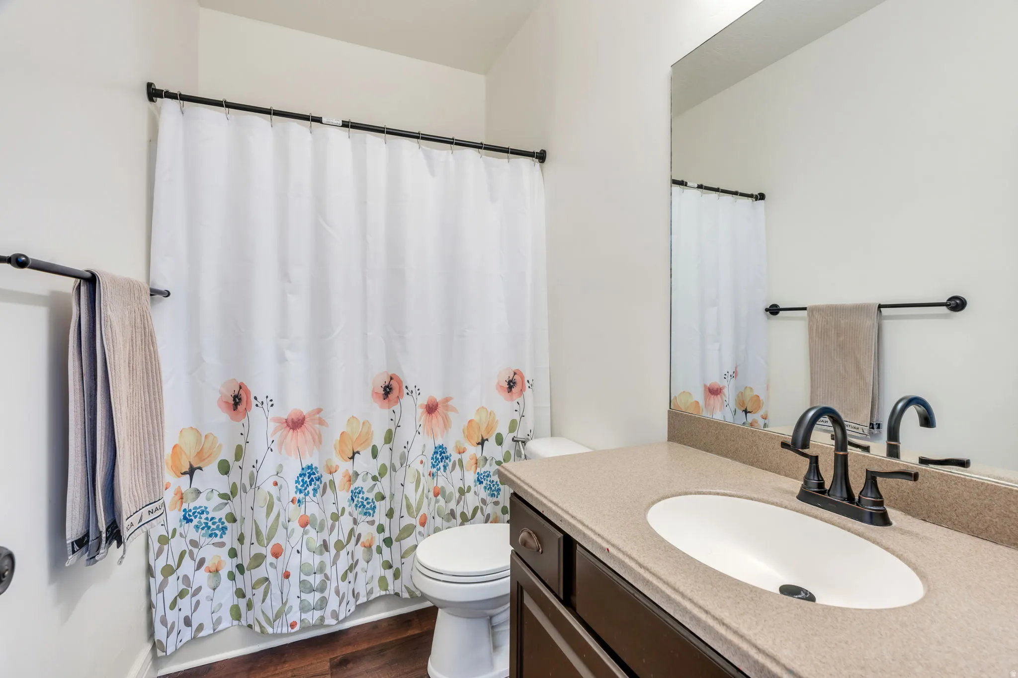 Vanity with an integrated oval sink, dark cabinet, and mounted mirror