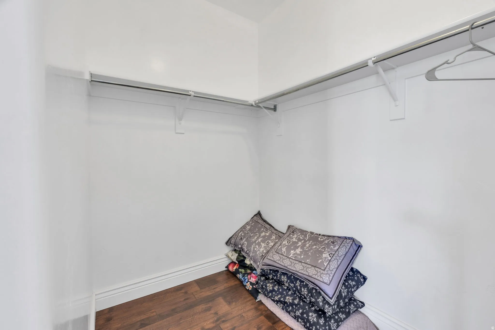 Primary room closet, white walls with wood-finish flooring