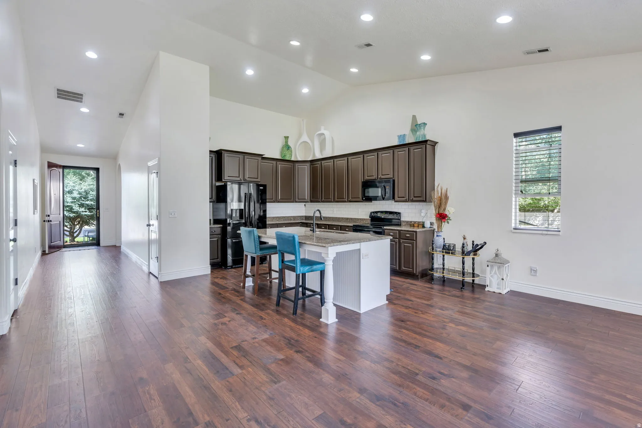 Open-concept living area featuring wood-finish flooring, vaulted ceilings, and recessed lighting