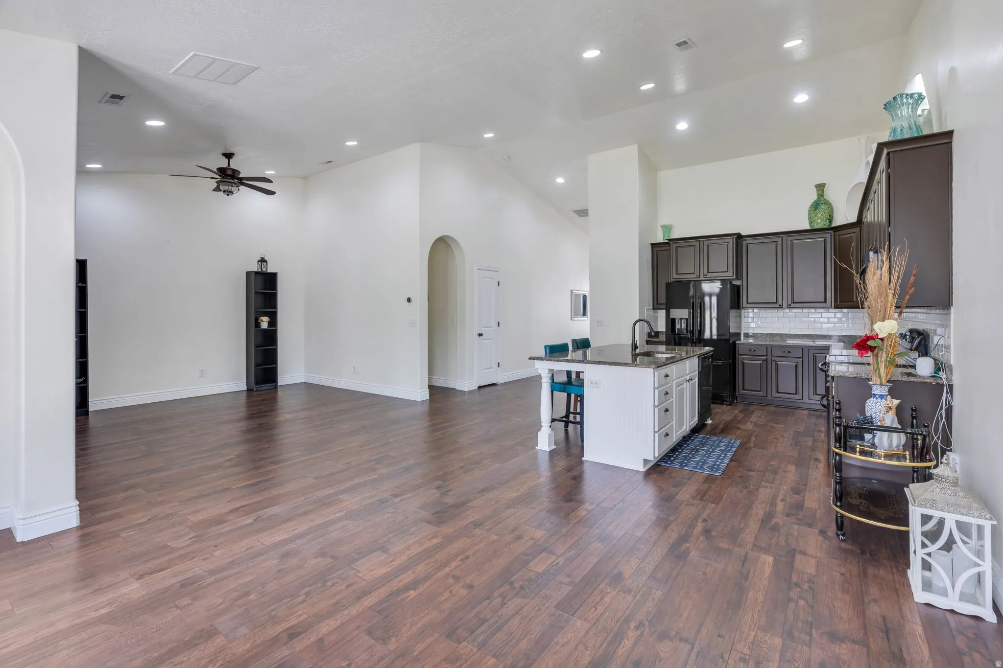 Expansive wood-finish flooring throughout, vaulted ceilings, recessed lighting, kitchen island with seating, and dark wood-finish cabinetry