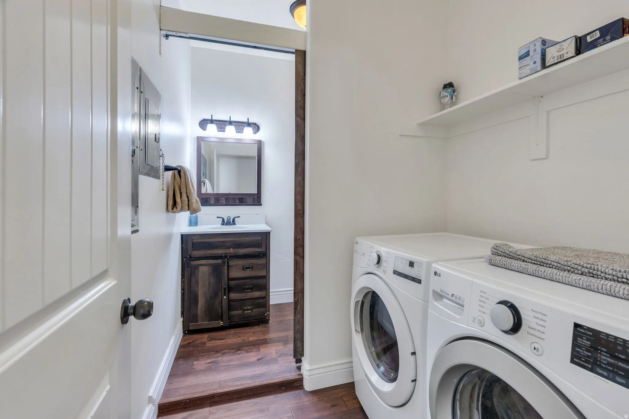 White paneled door with dark hardware, wood-finish flooring, and white wall shelving