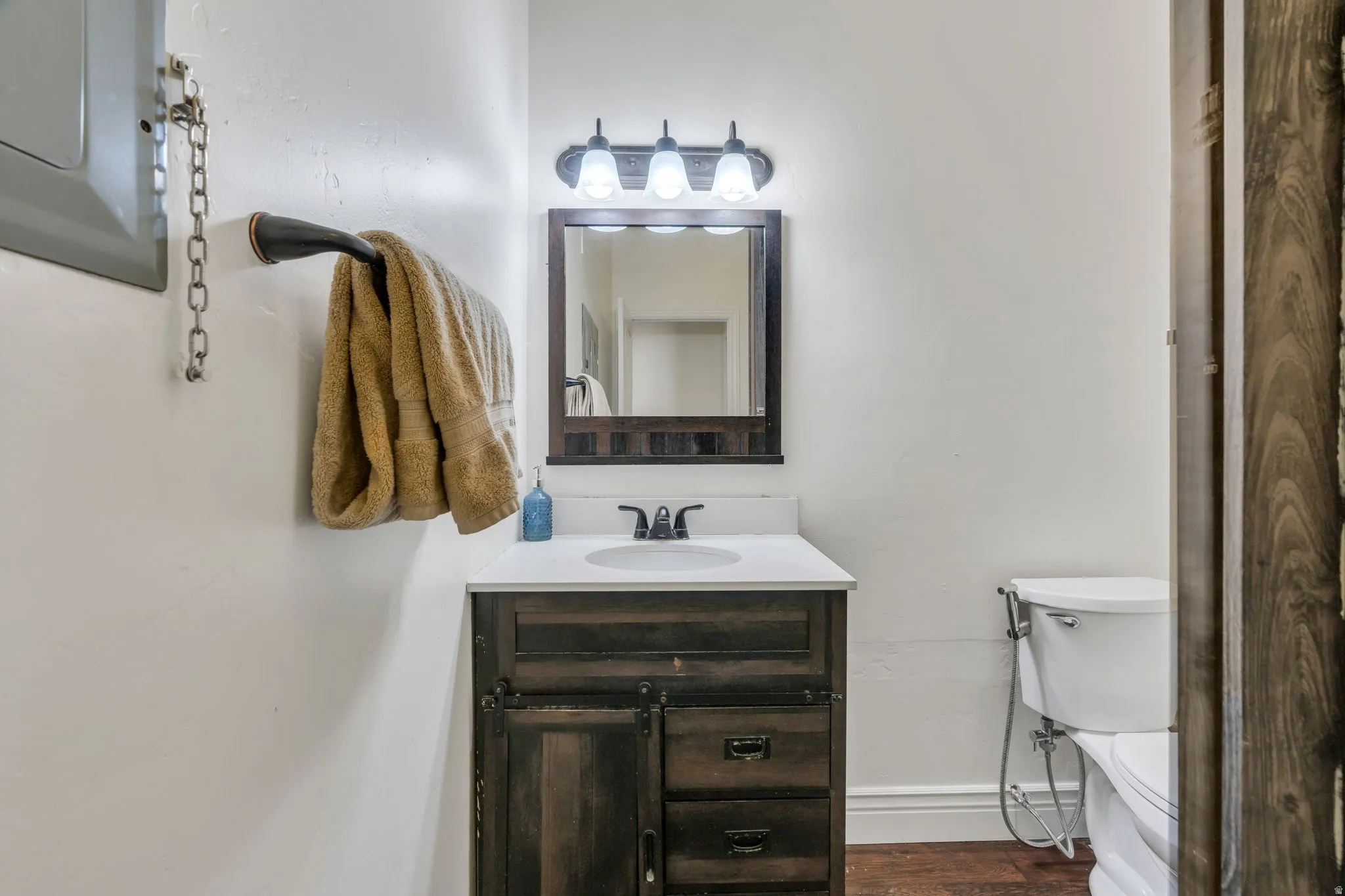 White countertop vanity with wood-finish cabinetry and rectangular sink
