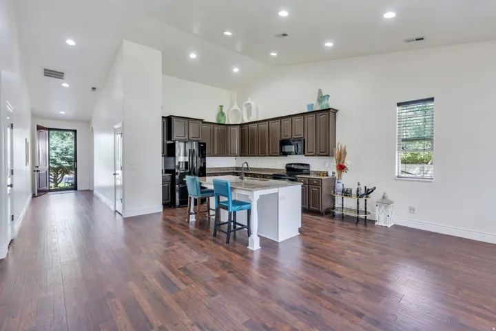 Open-concept living area featuring wood-finish flooring, vaulted ceilings, and recessed lighting