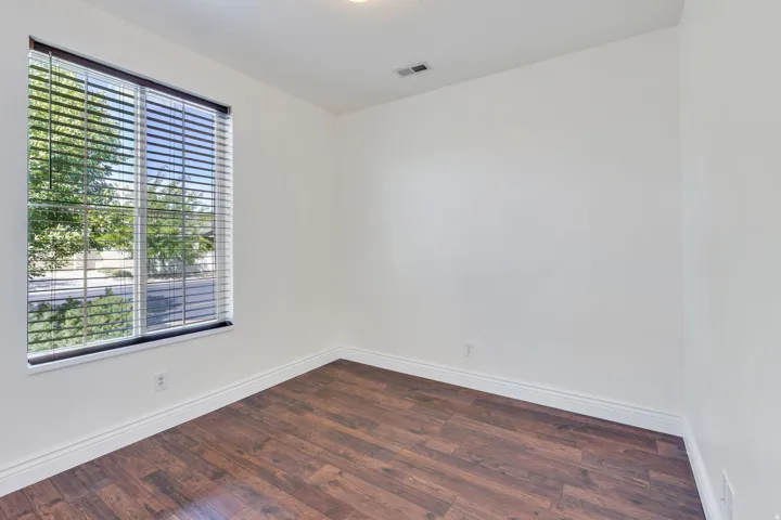 Wood-finish flooring, white walls, and a window with blinds