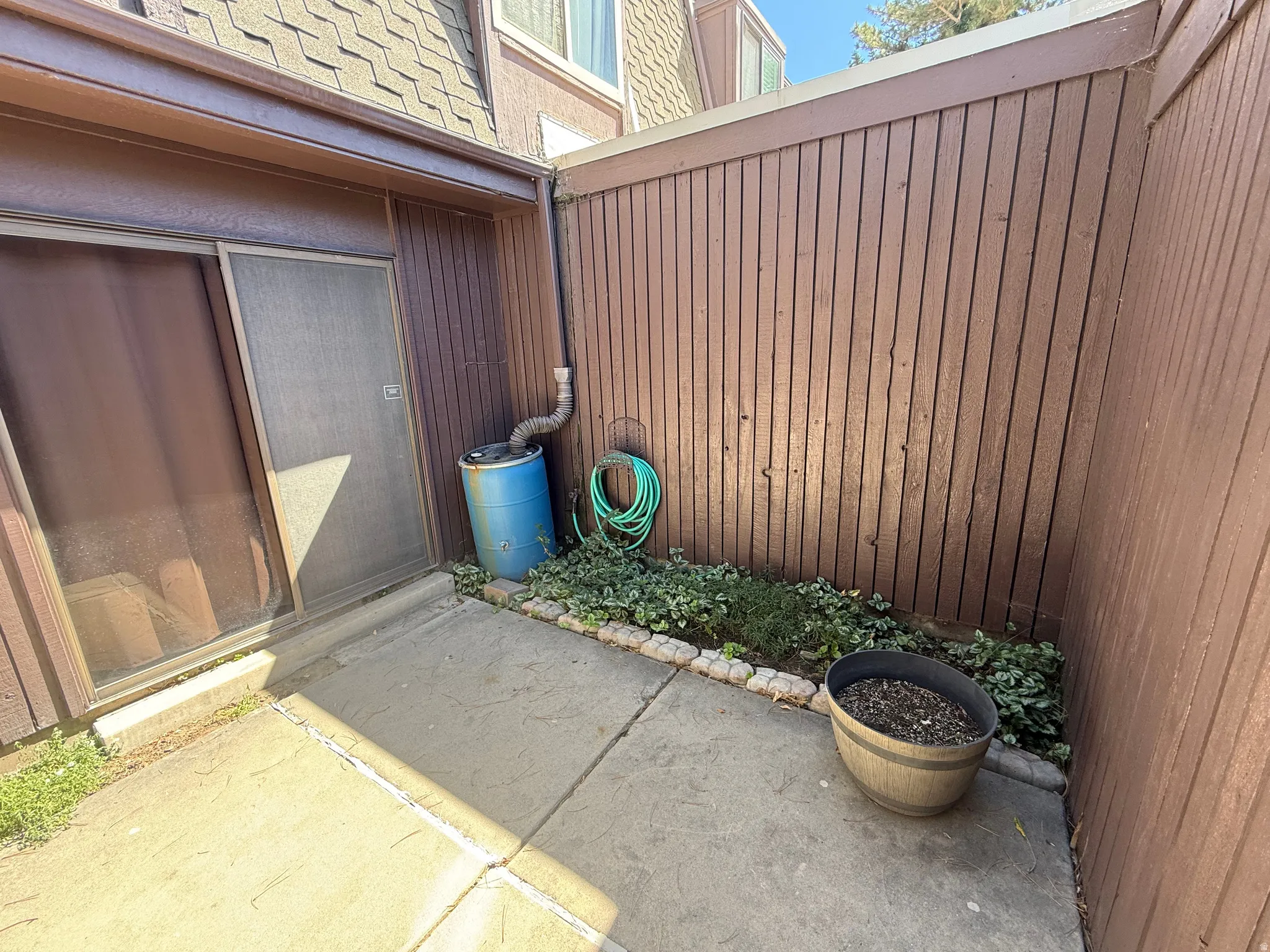Concrete patio area featuring vertical wood paneling and a sliding screen door