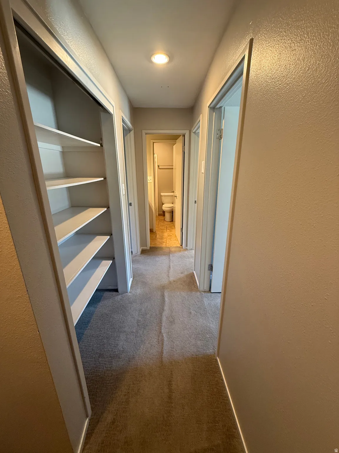 Hallway with neutral carpet flooring, recessed ceiling lighting, and built-in shelving
