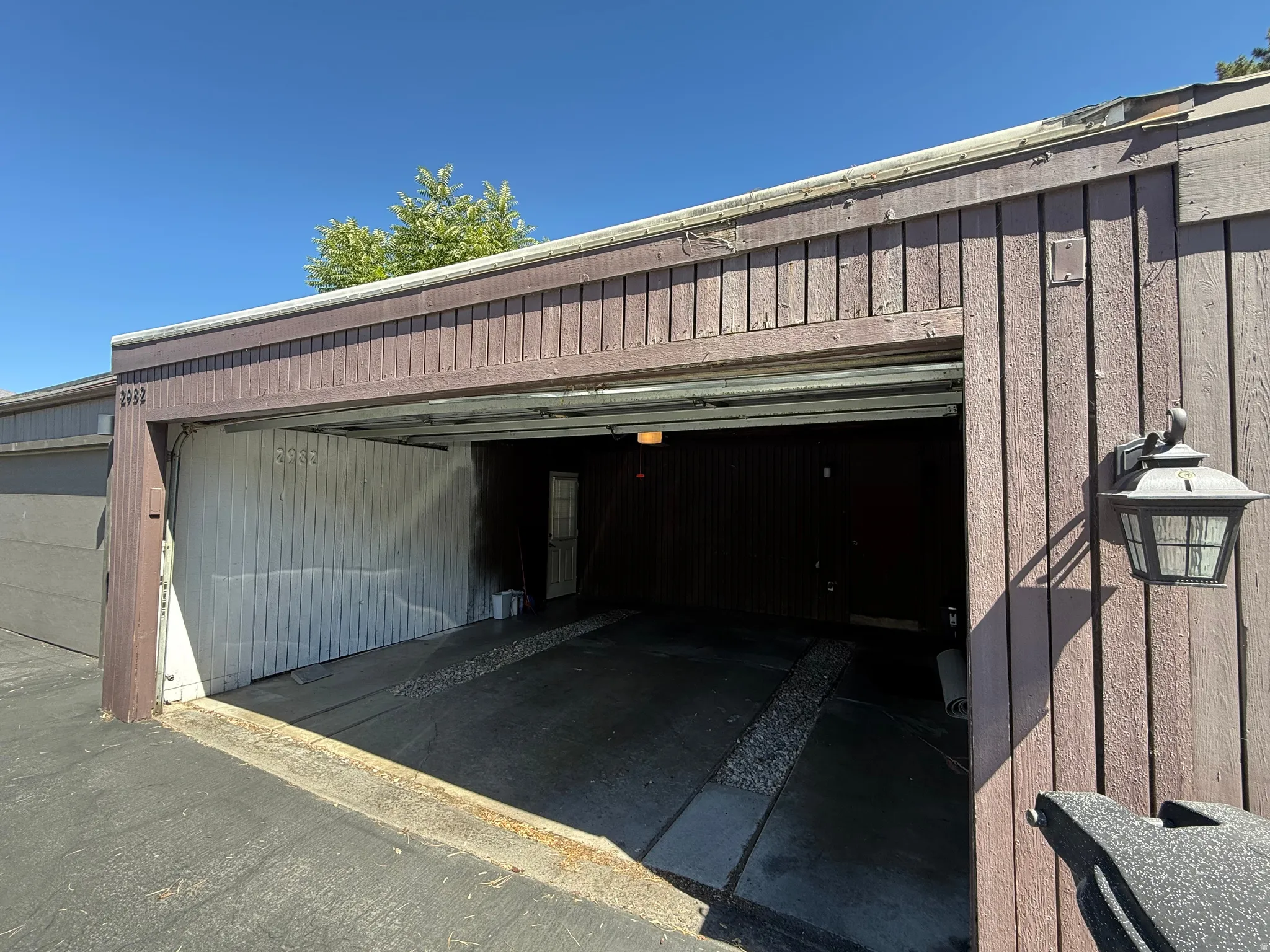 Attached garage bay with a built-in exterior light fixture and wood panel siding