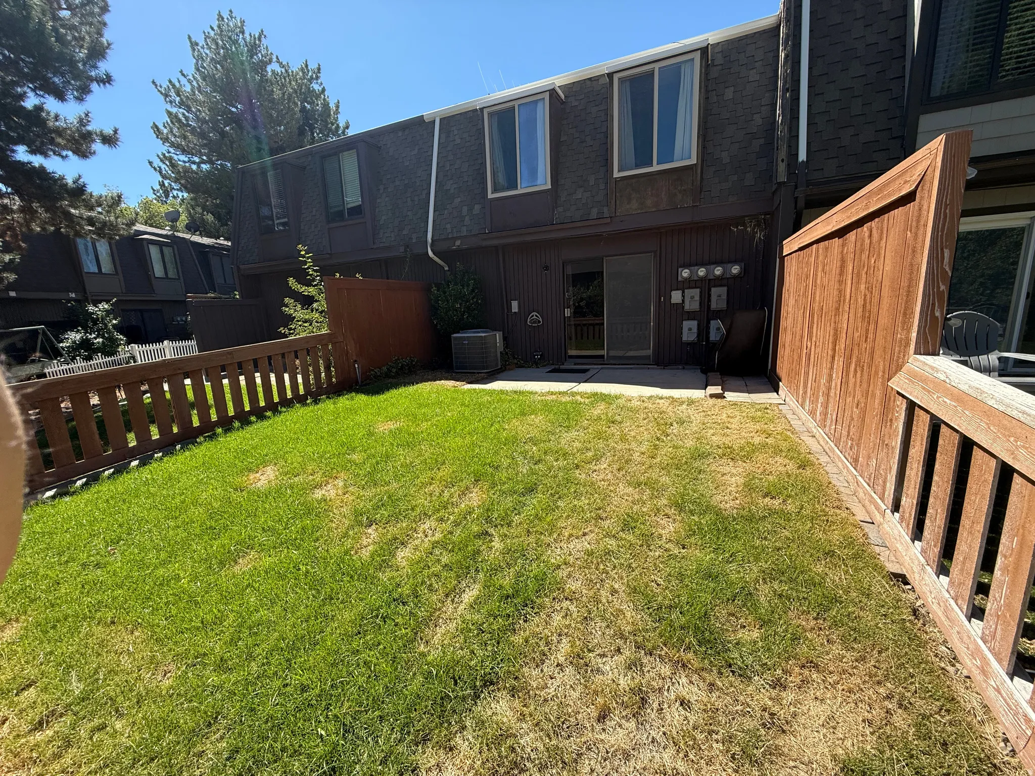Private fenced yard featuring a patio, sliding glass door access, and wood-paneled exterior