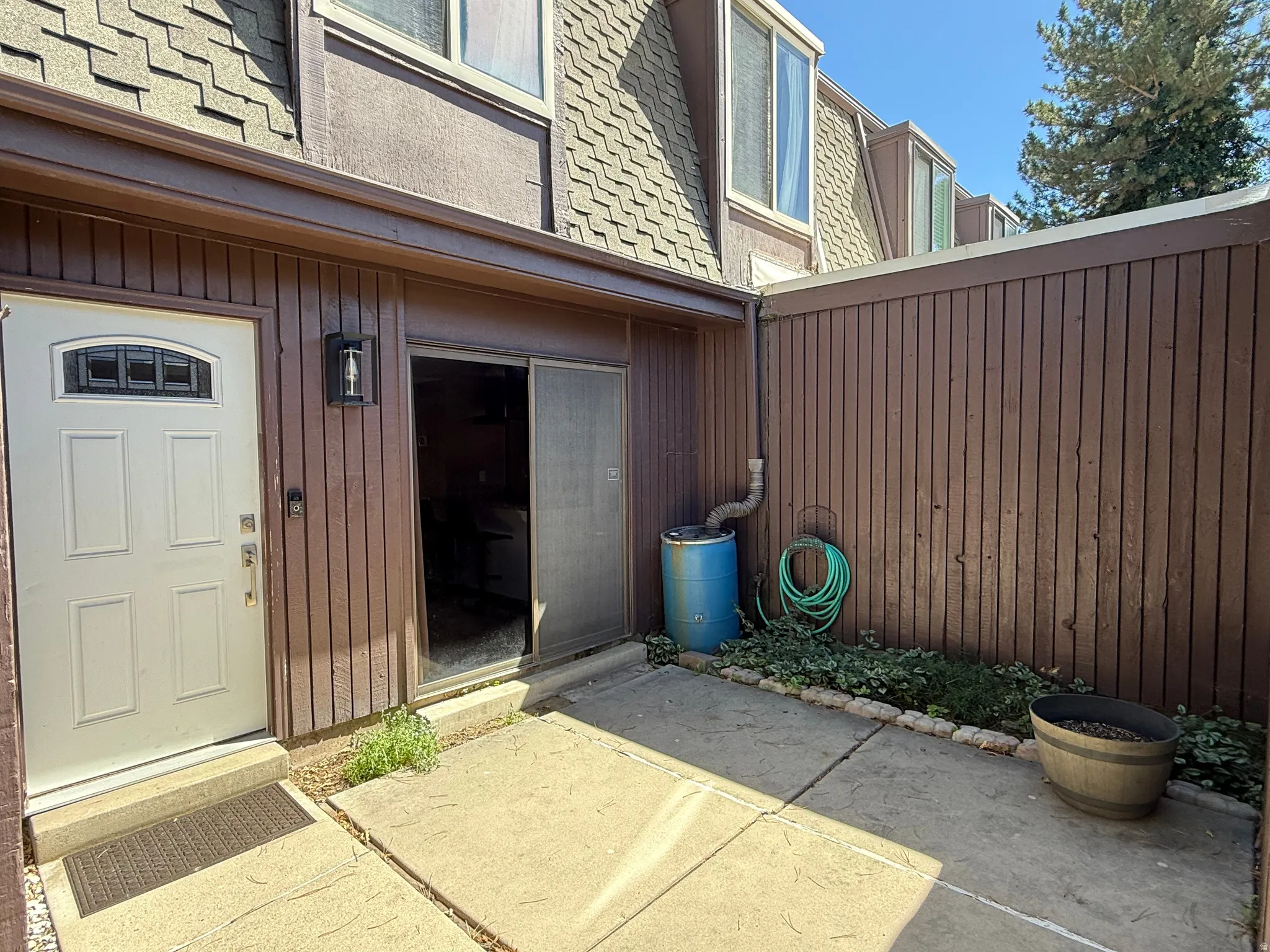 Exterior features a paneled front door with decorative glass, an exterior wall light, and brown vertical siding
