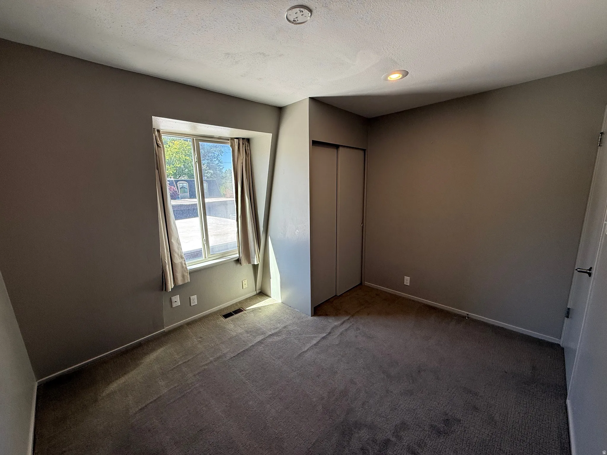 Carpeted room with a window, recessed lighting, and a bi-fold closet