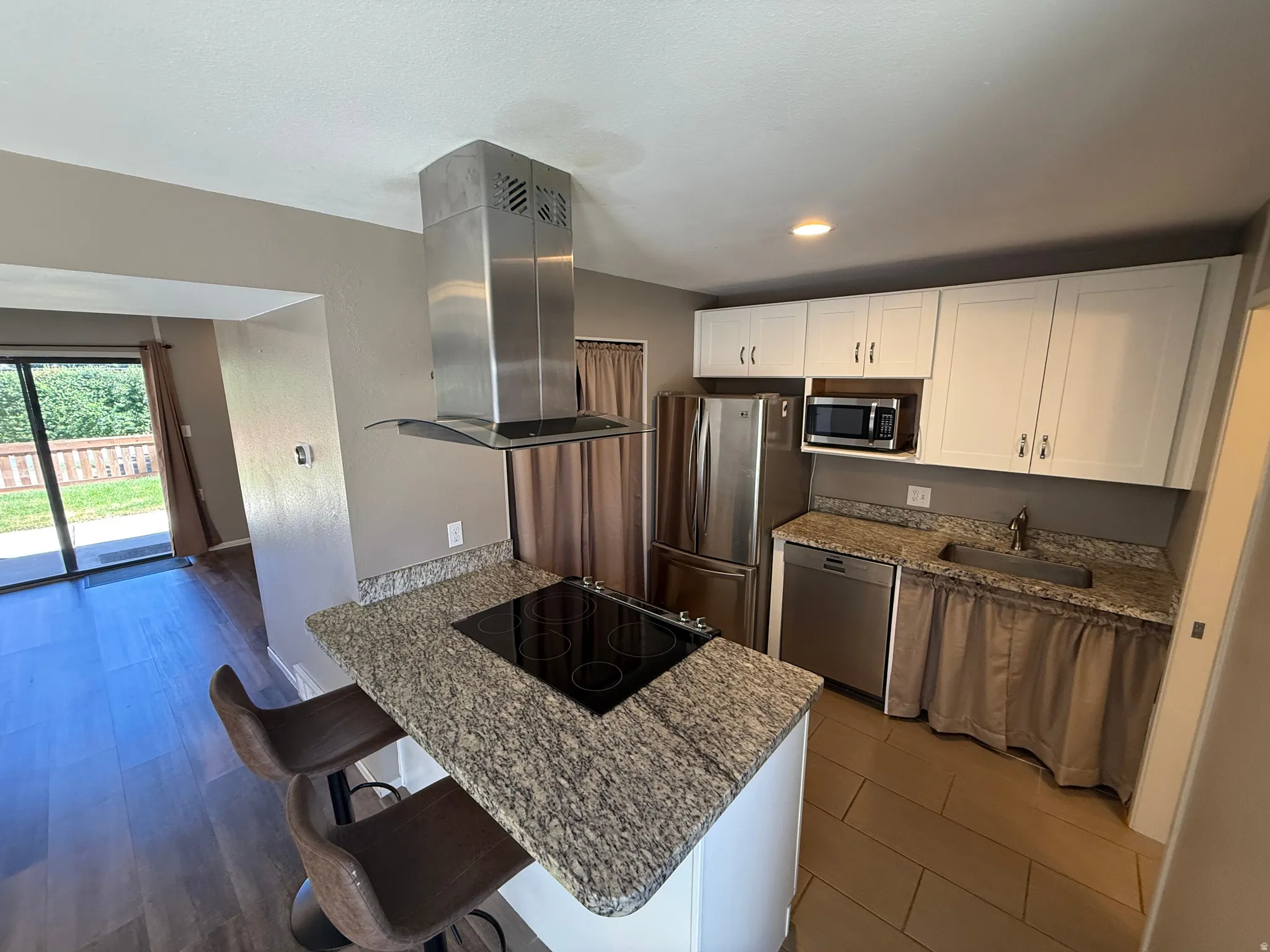 Kitchen featuring white cabinetry, stainless steel appliances, granite countertops, and tile flooring