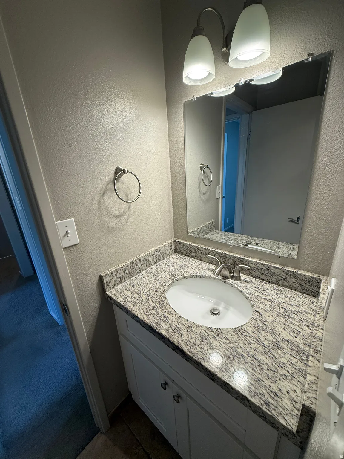White vanity with brushed nickel hardware, granite-style countertop, undermount oval sink, and brushed nickel faucet
