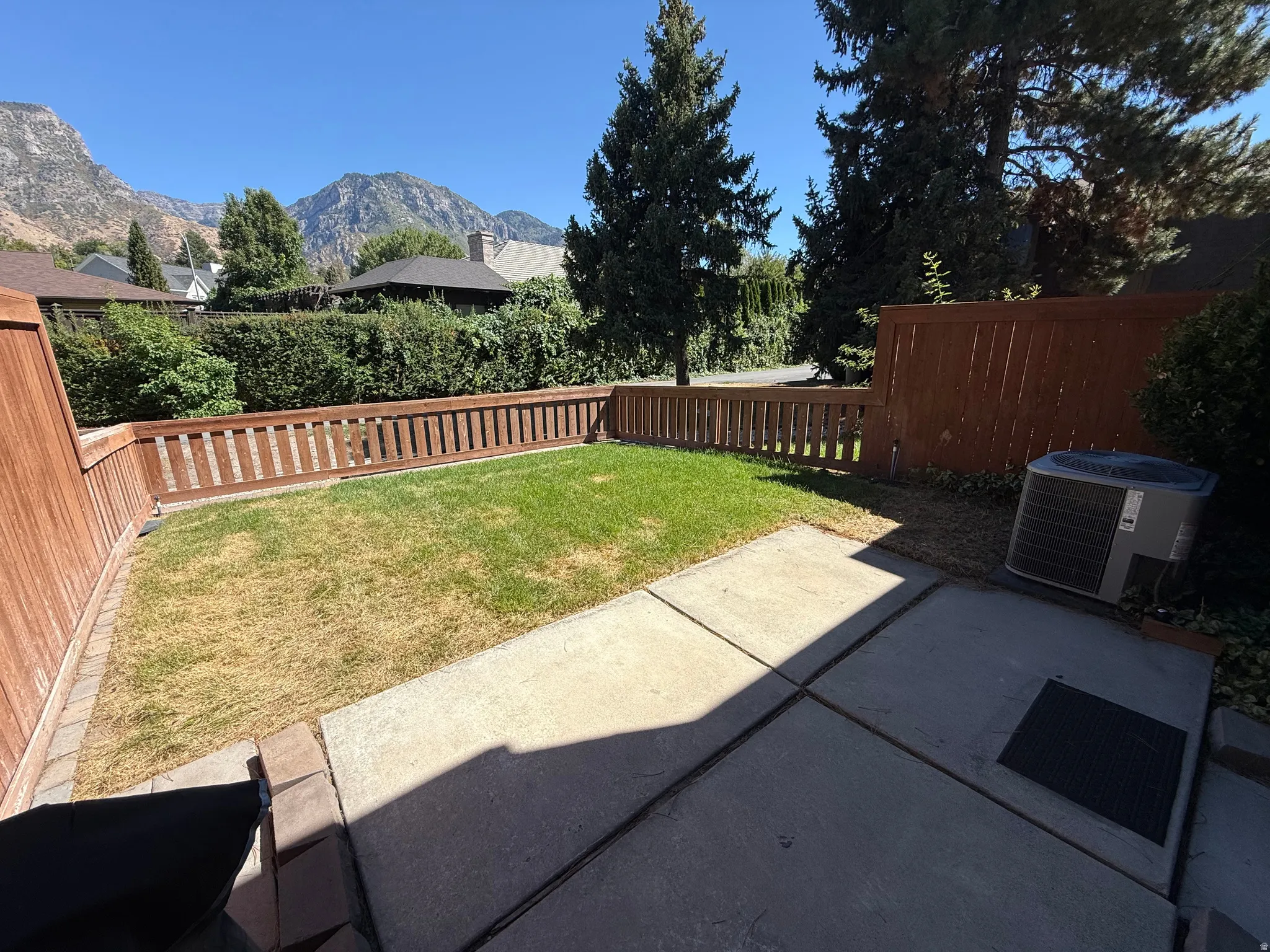 Private backyard featuring a concrete patio, grassy area, and wood fencing