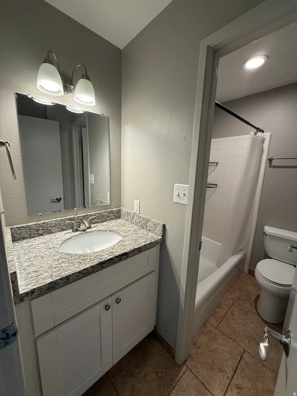 Vanity with a granite countertop, undermount sink, and white cabinetry