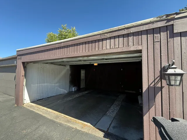 Attached garage bay with a built-in exterior light fixture and wood panel siding