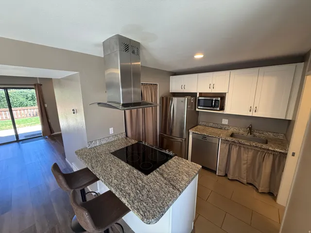 Kitchen featuring white cabinetry, stainless steel appliances, granite countertops, and tile flooring