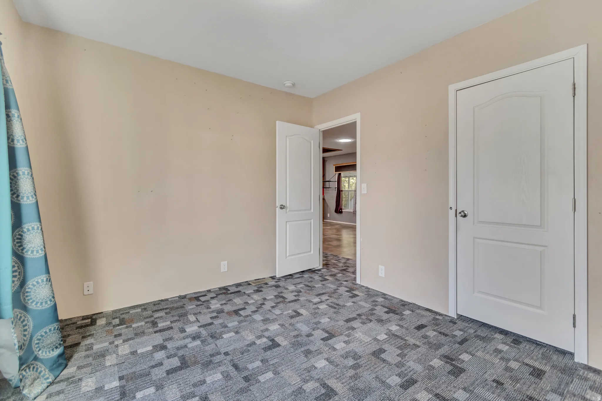 Neutral wall paint, patterned carpeting, and white interior doors