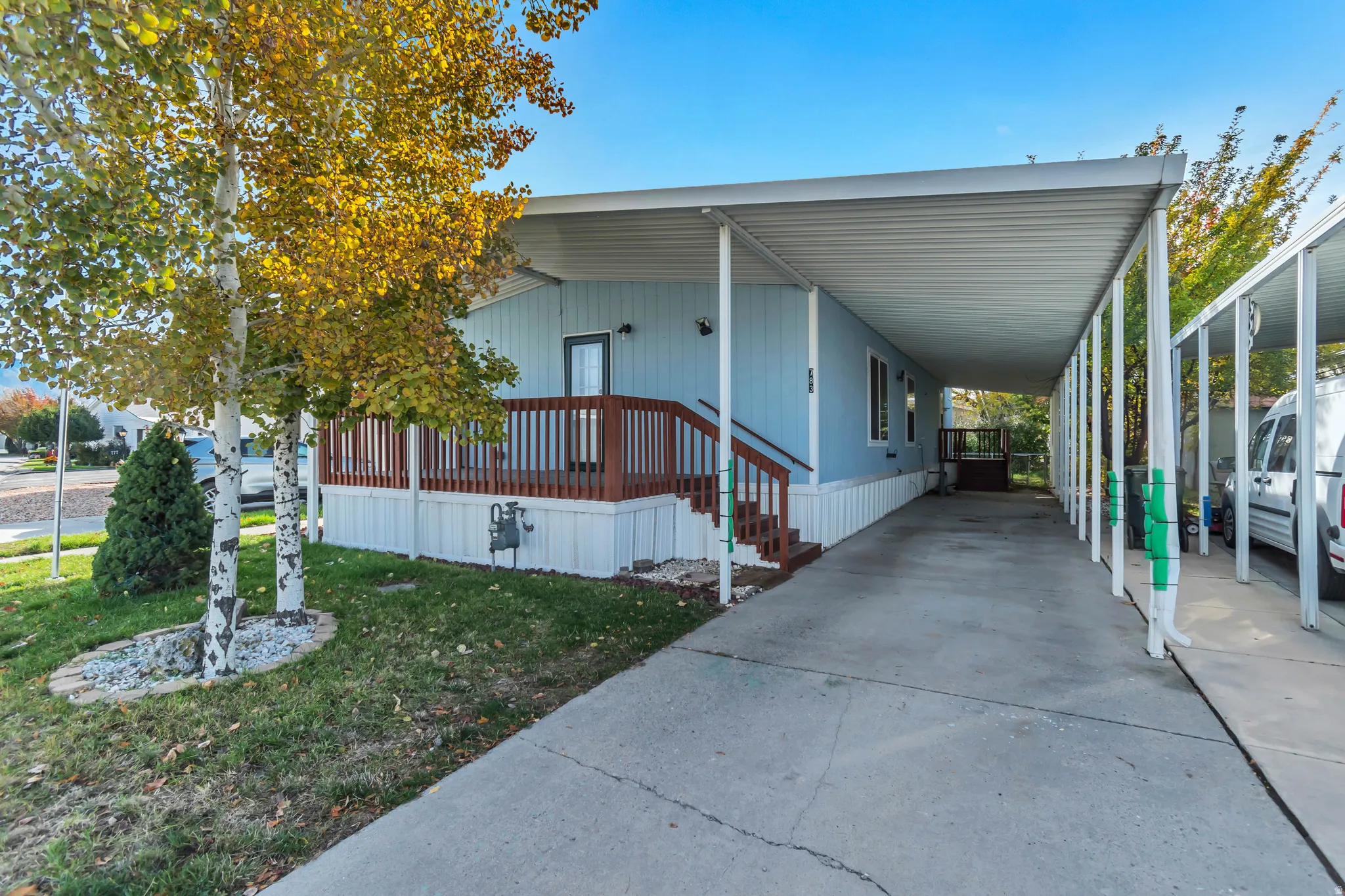 Exterior with light blue siding, white trim, and a covered porch featuring wood-finish railings
