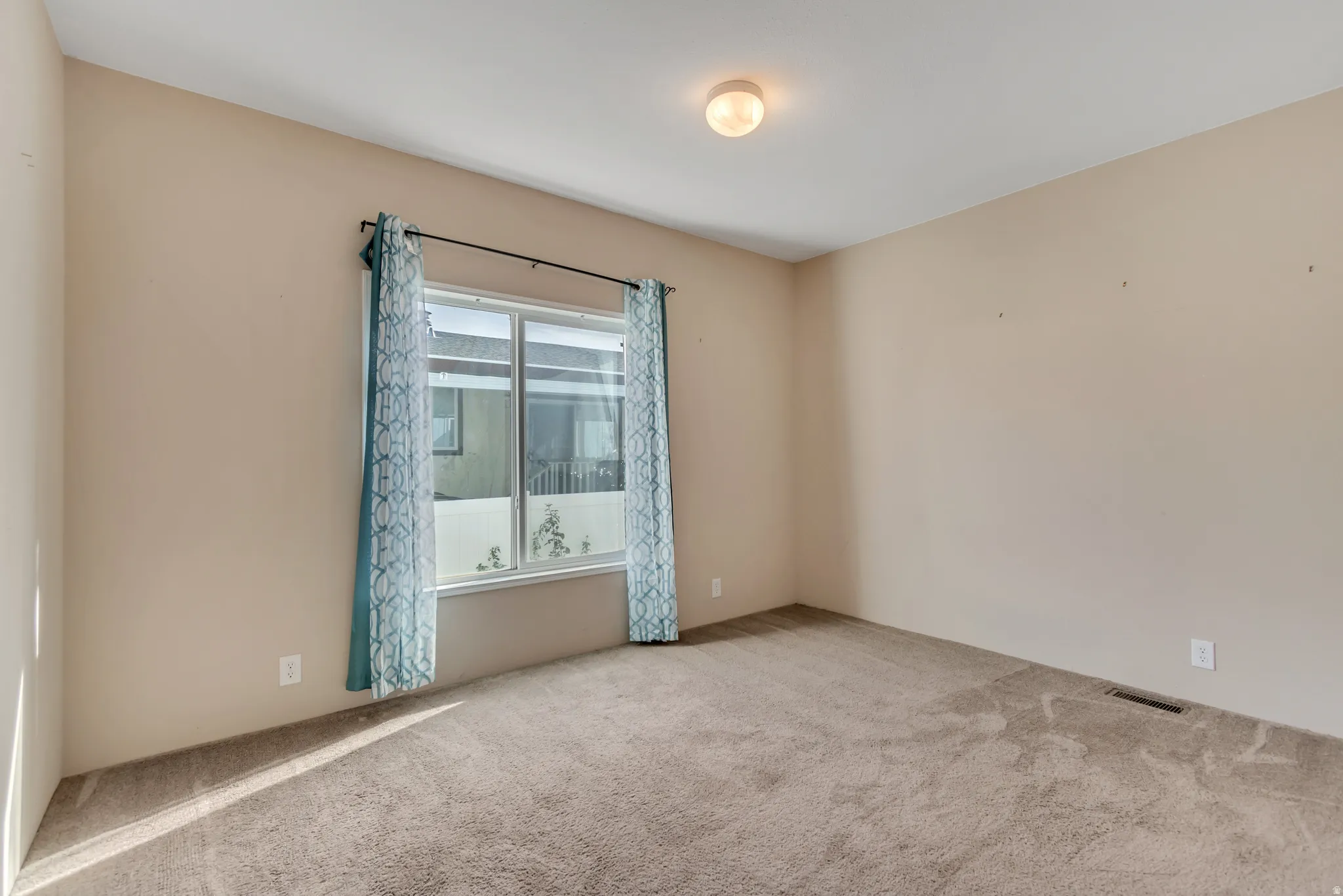 Light beige wall paint, single window, wall-to-wall carpeting, and flush mount ceiling light