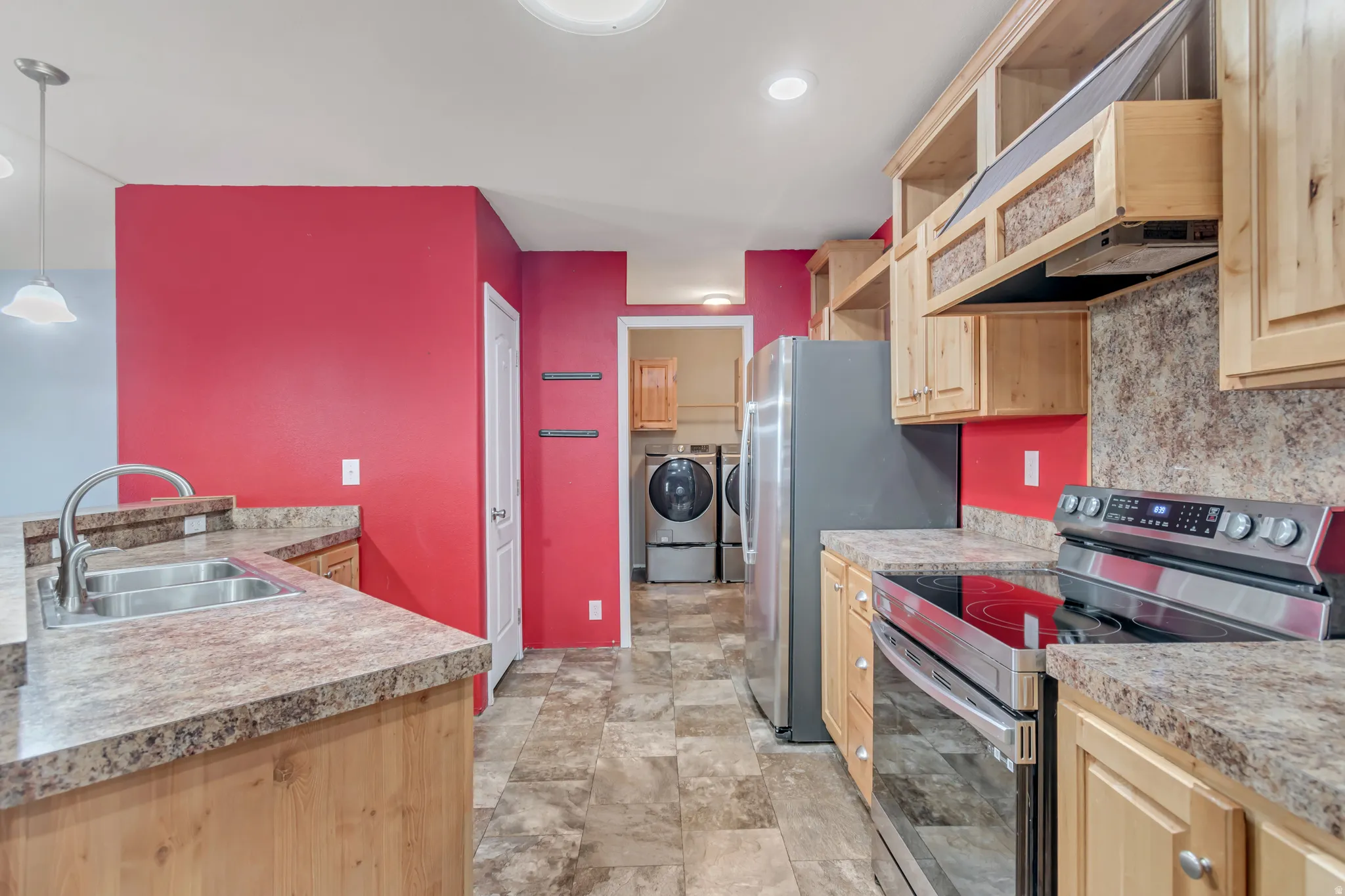 Kitchen with light wood-finish cabinetry, stainless steel sink, and speckled countertops