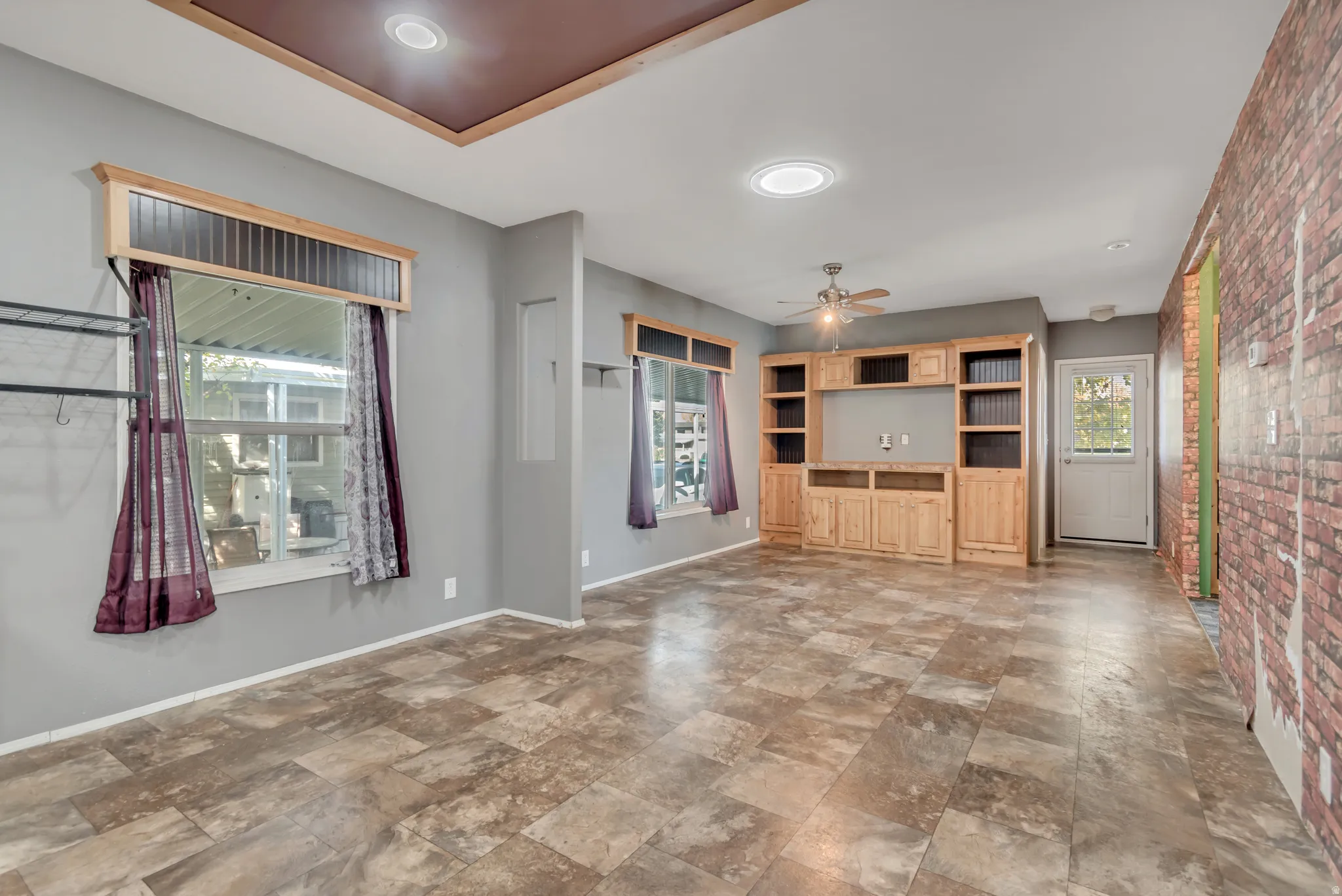 Built-in cabinetry with open shelving and lower storage, wood-finish flooring, ceiling fan, recessed lighting, and a white paneled door with glass insert