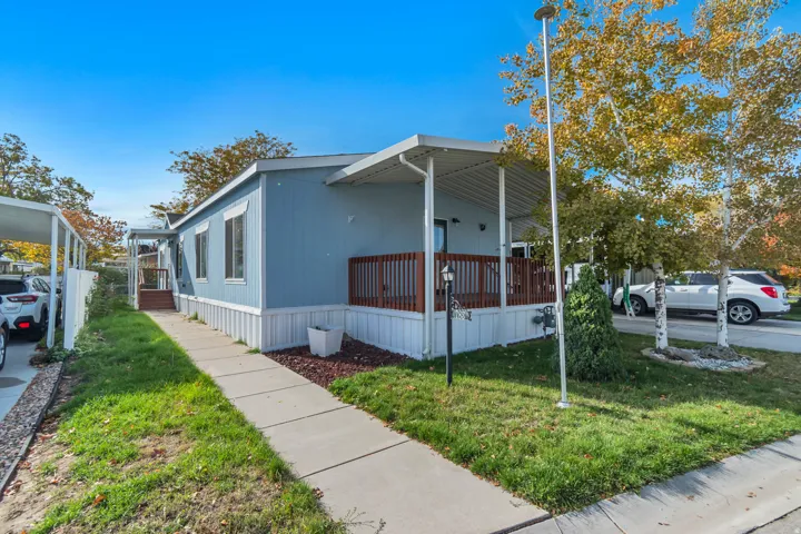 Exterior featuring a covered porch, wood railing, concrete walkway, and a carport