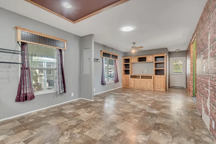 Built-in cabinetry with open shelving and lower storage, wood-finish flooring, ceiling fan, recessed lighting, and a white paneled door with glass insert