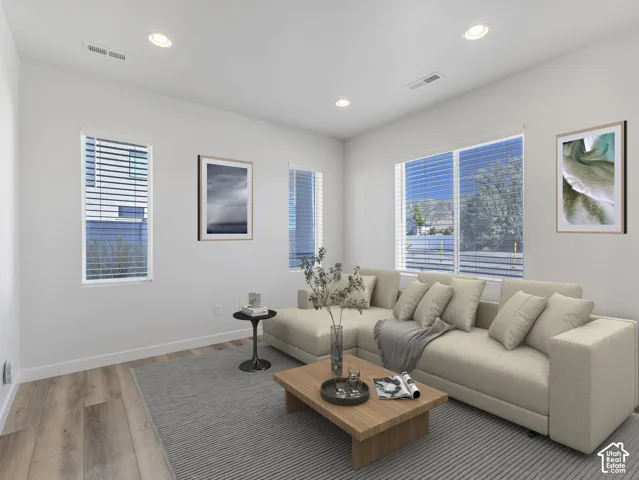 Recessed lighting, multiple windows with blinds, wood-finish flooring, and white walls