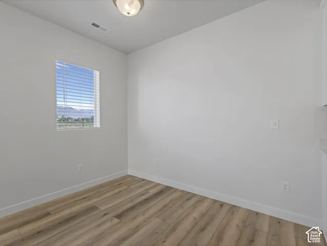 Recessed window with horizontal blinds, wood-finish flooring, white walls, and a ceiling-mounted light fixture