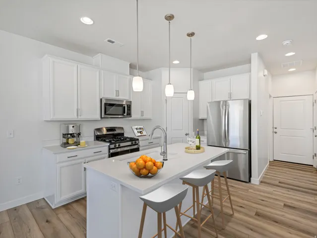 Contemporary kitchen featuring white cabinetry, stainless steel appliances, a center island with pendant lighting, recessed lighting, and wood-finish flooring