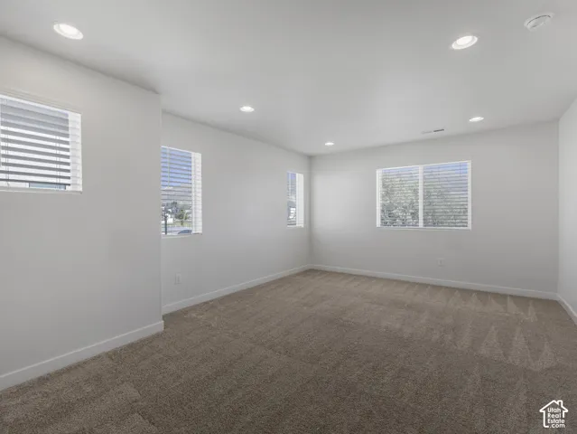 Recessed lighting, multiple windows with blinds, and neutral carpet flooring
