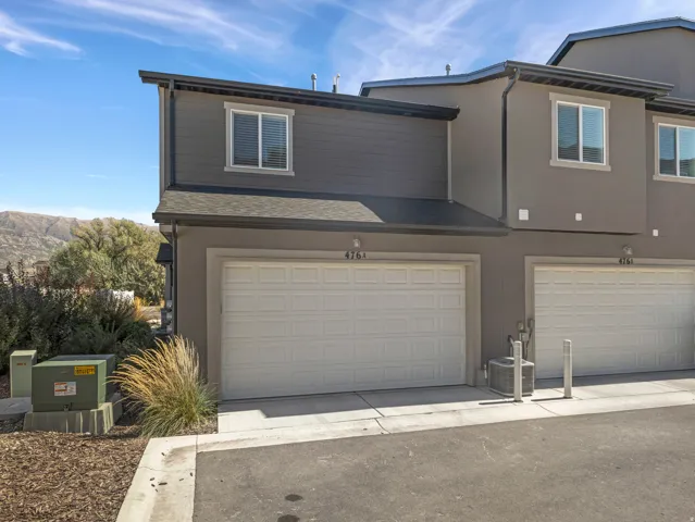 Modern two-story exterior featuring a single-car garage, stucco finish, and horizontal siding accents