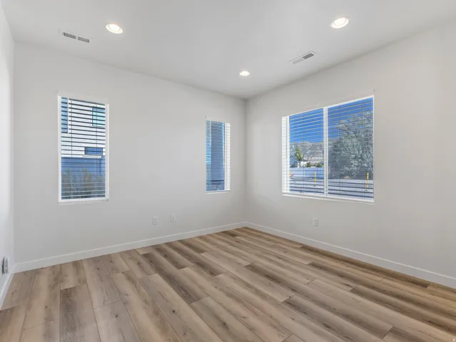 Recessed ceiling lighting, multiple windows with blinds, wood-finish flooring, and white baseboards